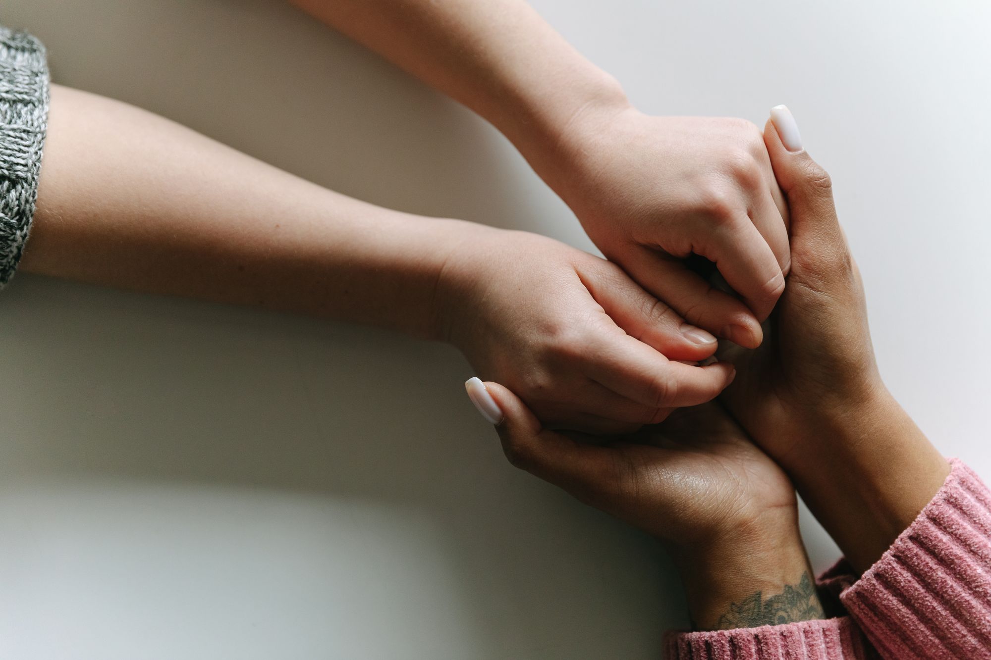 Two pairs of hands clasped together in a gesture of support.